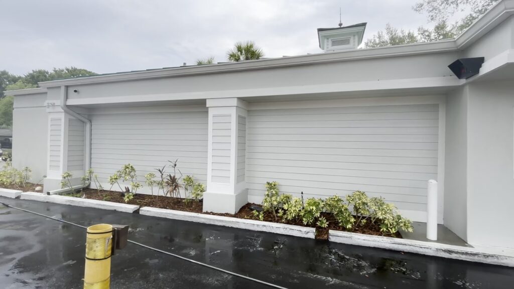 Documented commercial exterior wall with white columns and gray horizontal siding