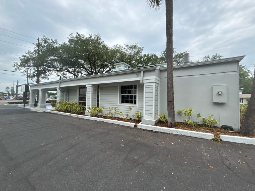 Wide documented view of a gray commercial exterior with white trim and landscaped frontage
