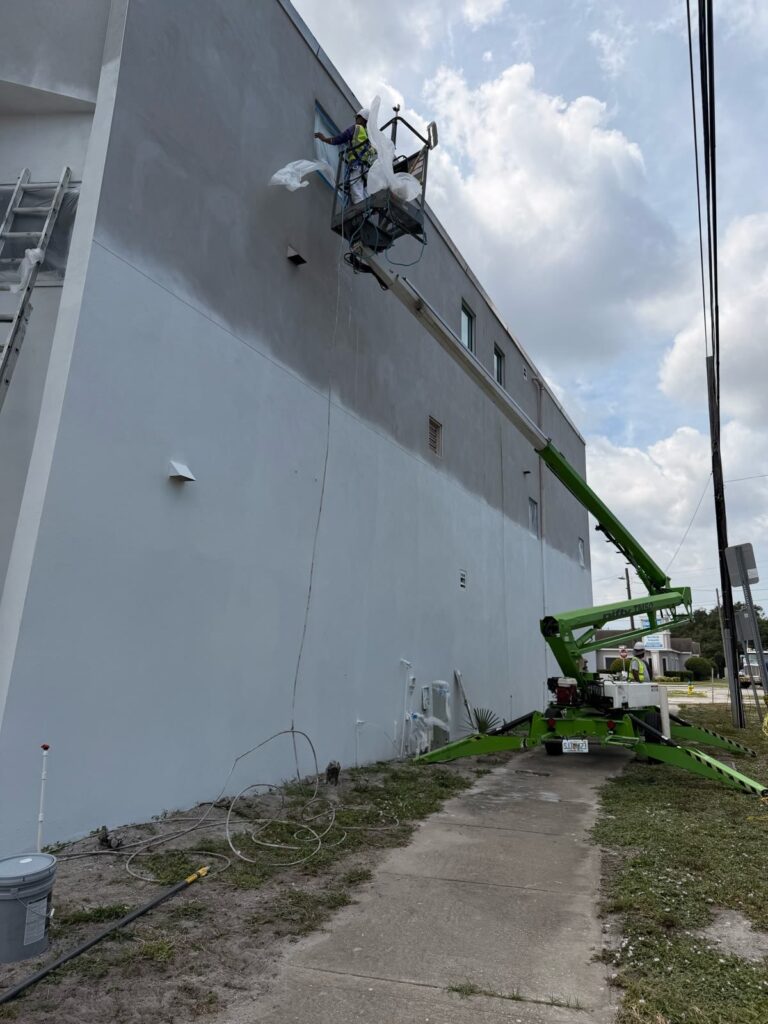 Commercial exterior painting in progress using lift access